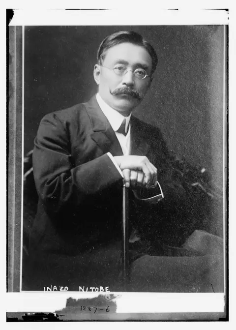Photograph of Nitobe Inazō, seated, with glasses and one hand on a cane; his name is handwritten on the negative