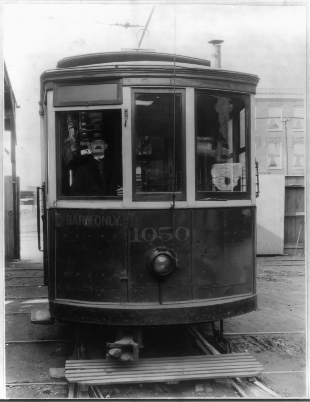 Motorman at the front window of a streetcar on its tracks, in a 1923 photograph
